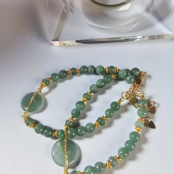 Blauwasser Jade Armband Naturstein -PER-02-03 Handgefertigtes Jade Armband aus blau-grünen Jade-Perlen mit goldenen Trennperlen und einem runden Jade-Anhänger (Ping-An-Knopf). Eleganter Schmuck mit traditioneller chinesischer Symbolik.