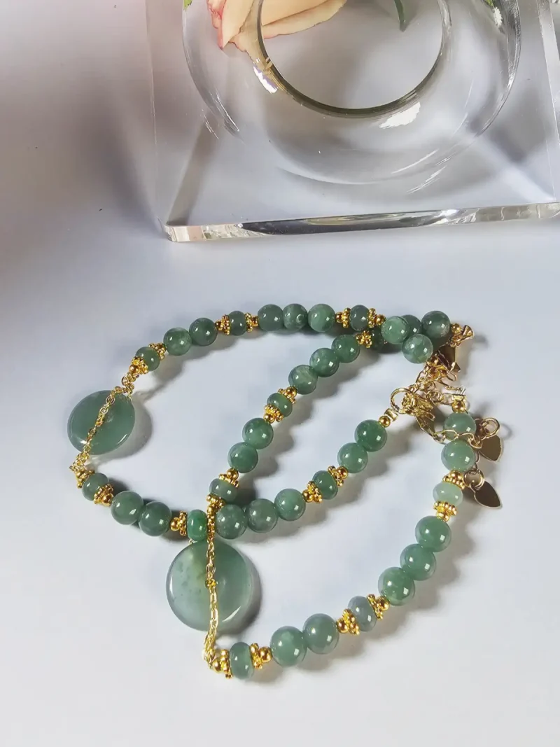 Blauwasser Jade Armband Naturstein -PER-02-03 Handgefertigtes Jade Armband aus blau-grünen Jade-Perlen mit goldenen Trennperlen und einem runden Jade-Anhänger (Ping-An-Knopf). Eleganter Schmuck mit traditioneller chinesischer Symbolik.