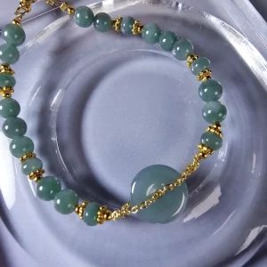 Handgefertigtes Jade Armband aus blau-grünen Jade-Perlen mit goldenen Trennperlen und einem runden Jade-Anhänger (Ping-An-Knopf). Eleganter Schmuck mit traditioneller chinesischer Symbolik.