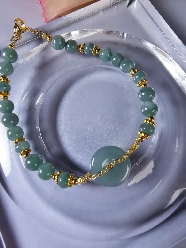 Jade Perlen Armband mit Gold-Akzente, Blauwasser Jade- ein Glücksbringer Handgefertigtes Jade Armband aus blau-grünen Jade-Perlen mit goldenen Trennperlen und einem runden Jade-Anhänger (Ping-An-Knopf). Eleganter Schmuck mit traditioneller chinesischer Symbolik.