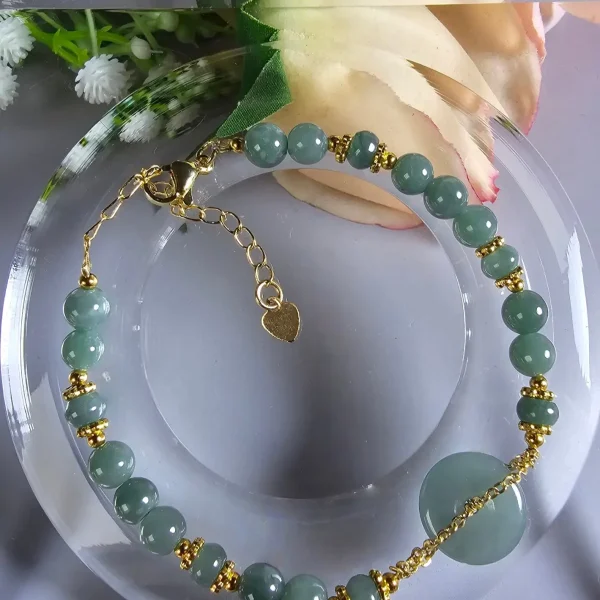 AB-PER-02-07 Handgefertigtes Jade Armband aus blau-grünen Jade-Perlen mit goldenen Trennperlen und einem runden Jade-Anhänger (Ping-An-Knopf). Eleganter Schmuck mit traditioneller chinesischer Symbolik.