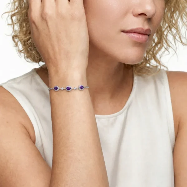 Amethyst Armband aus Kupfer versilbert Nahaufnahme einer Frau in einem hellen ärmellosen Oberteil, die ein filigranes Silberfarbe Armband mit drei violetten Amethyst Edelsteinen und kleinen funkelnden Zirkonia Akzenten am Handgelenk trägt.