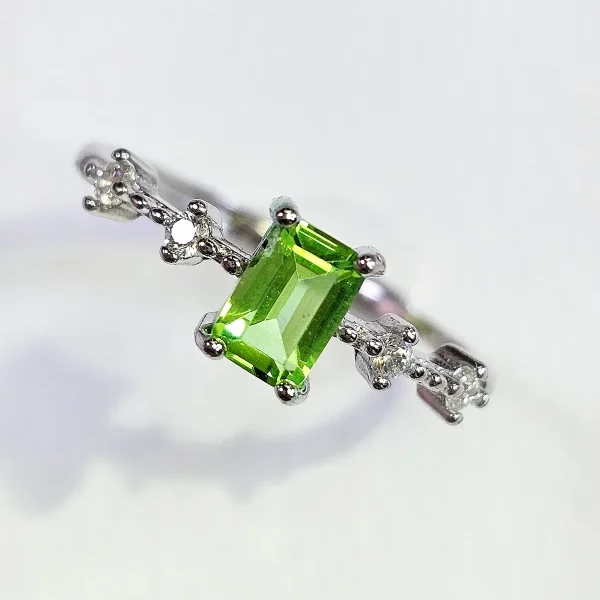 DR-SIL-03-2 ein 925er eckiger Peridot-Ring mit grünem Peridot Edelstein und Zirkonia, Geometrisch Look, Smaragdschliff (Emerald Cut), Hauptstein in rechteckiges design, vor ein weißer Hintergrund