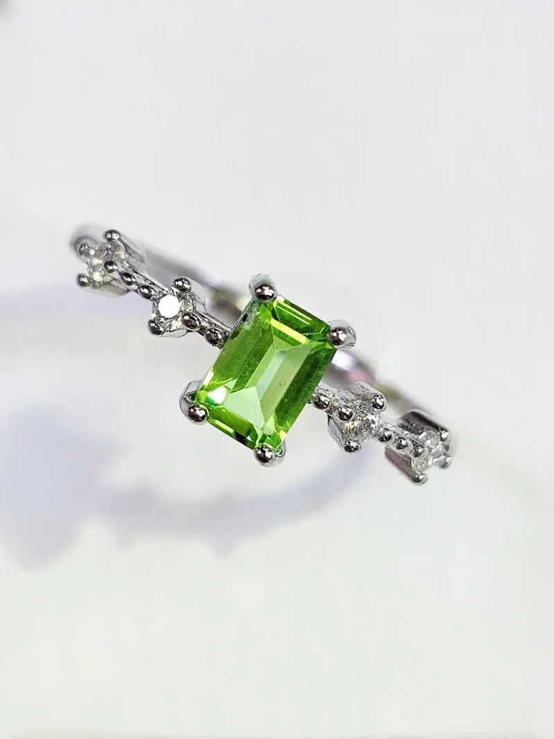 DR-SIL-03-2 ein 925er eckiger Peridot-Ring mit grünem Peridot Edelstein und Zirkonia, Geometrisch Look, Smaragdschliff (Emerald Cut), Hauptstein in rechteckiges design, vor ein weißer Hintergrund