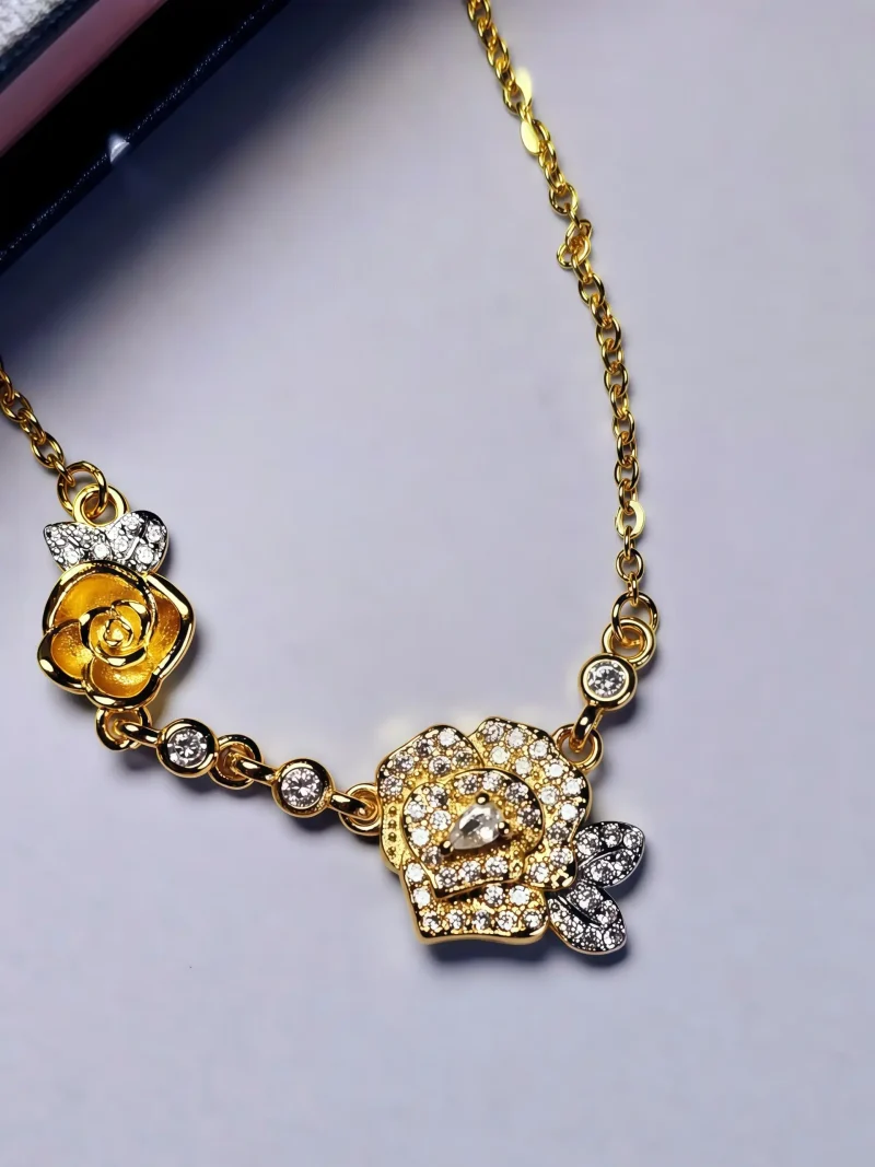 Luxuriöse Rosengold-Halskette mit Kristallbesatz – Filigranes Doppel-Blüten Design Eine zarte zweifarbige Halskette mit einem Anhänger aus zwei Rosen: eine ist eine dreidimensionale goldene Rose, die andere eine silberne Rose, die mit funkelnden Zirkonia-Steinen besetzt ist.