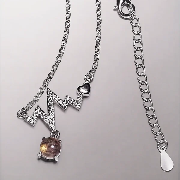 Elegante Modeschmuck Halskette mit einem Zickzack-Anhänger, funkelnden Zirkonia, einem herzförmigen Detail und einem braunen Rutilquarz-Anhänger.