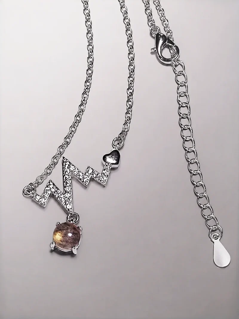 Elegante Modeschmuck Halskette mit einem Zickzack-Anhänger, funkelnden Zirkonia, einem herzförmigen Detail und einem braunen Rutilquarz-Anhänger.