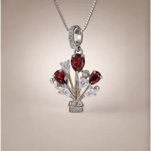 ein Modeschmuck Halskette mit roter Granat Naturstein Anhänger- Luftballon-Design, vor einer weißen Hintergrund.