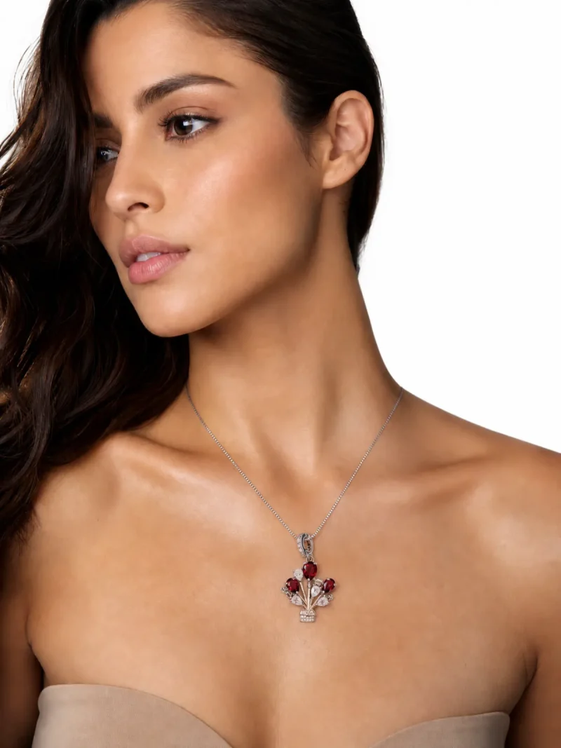 HK-TDS-10-07 ein Modeschmuck Halskette mit roter Granat Naturstein Anhänger- Luftballon-Design, getragen von einem Model zu einem schulterfreien cremefarbenen Oberteil vor weiße Hintergrund.