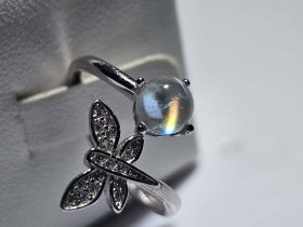Mondstein Ring Madagaskar Regenbogen Feuer Offener Mondstein Ring aus 925er Sterlingsilber mit einem leuchtenden madagassischen Mondstein, der ein faszinierendes Regenbogen-Feuer zeigt, verziert mit einem funkelnden Schmetterling aus Zirkonia.