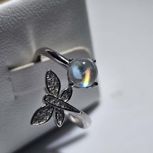 Offener Mondstein Ring aus 925er Sterlingsilber mit einem leuchtenden madagassischen Mondstein, der ein faszinierendes Regenbogen-Feuer zeigt, verziert mit einem funkelnden Schmetterling aus Zirkonia.