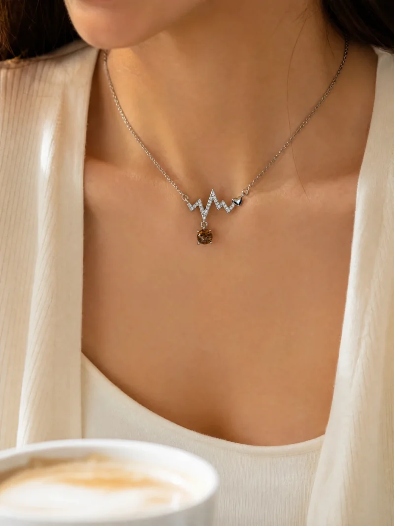 Lifestyle-Aufnahme einer S925 Sterling Silber Halskette mit geometrischem Zickzack-Design, funkelnden Zirkonia, kleinem Herzdetail und braunem Rutilquarz-Anhänger, getragen zu einem eleganten cremefarbenen Outfit.