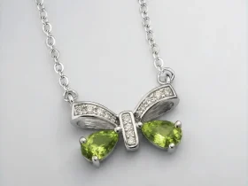 Schleife-HK05-01 ein 925er Silber Halskette mit grünem Peridot Edelstein Anhänger- Schmetterling, vor einer lichtblauer Hintergrund.
