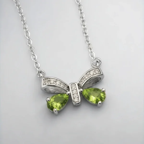 Schleife-HK05-01 ein 925er Silber Halskette mit grünem Peridot Edelstein Anhänger- Schmetterling, vor einer lichtblauer Hintergrund.