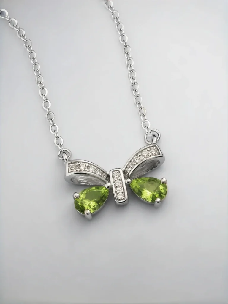 ein 925er Silber Halskette mit grünem Peridot Edelstein Anhänger- Schmetterling, vor einer lichtblauer Hintergrund.