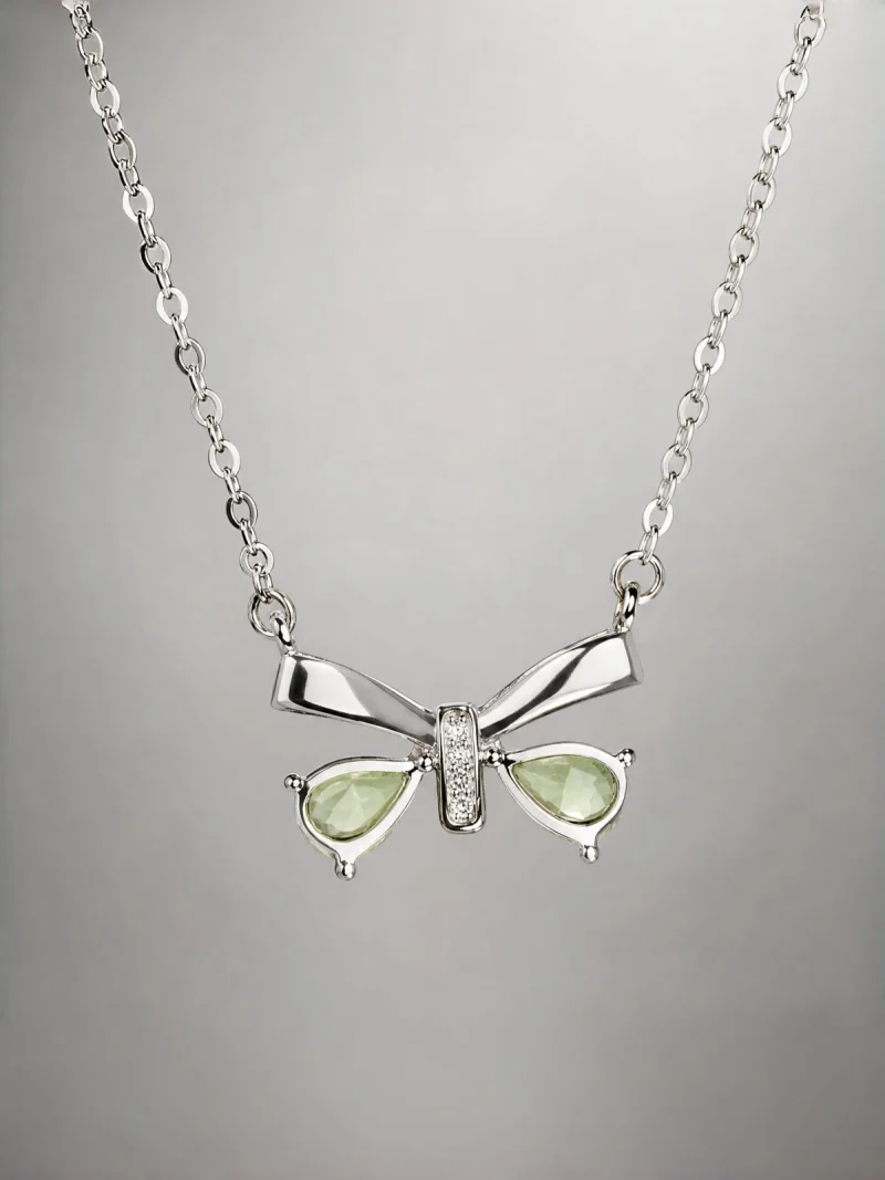Schleife-HK05-02 ein 925er Silber Halskette mit grünem Peridot Edelstein Anhänger- Schmetterling, vor einer lichtblauer Hintergrund.