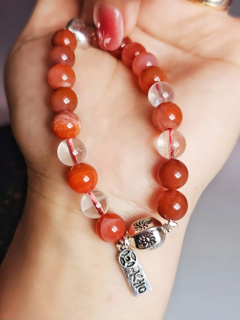 AB-ACT-02 Damenarmband aus rotem Achat Kugeln Bergkristall fein poliert versiberten Details mit chinesischen Schriftzeichen in der offenen Hand gezeigt. Ansicht der versilberten Details mit chinesischen Schriftzeichen.