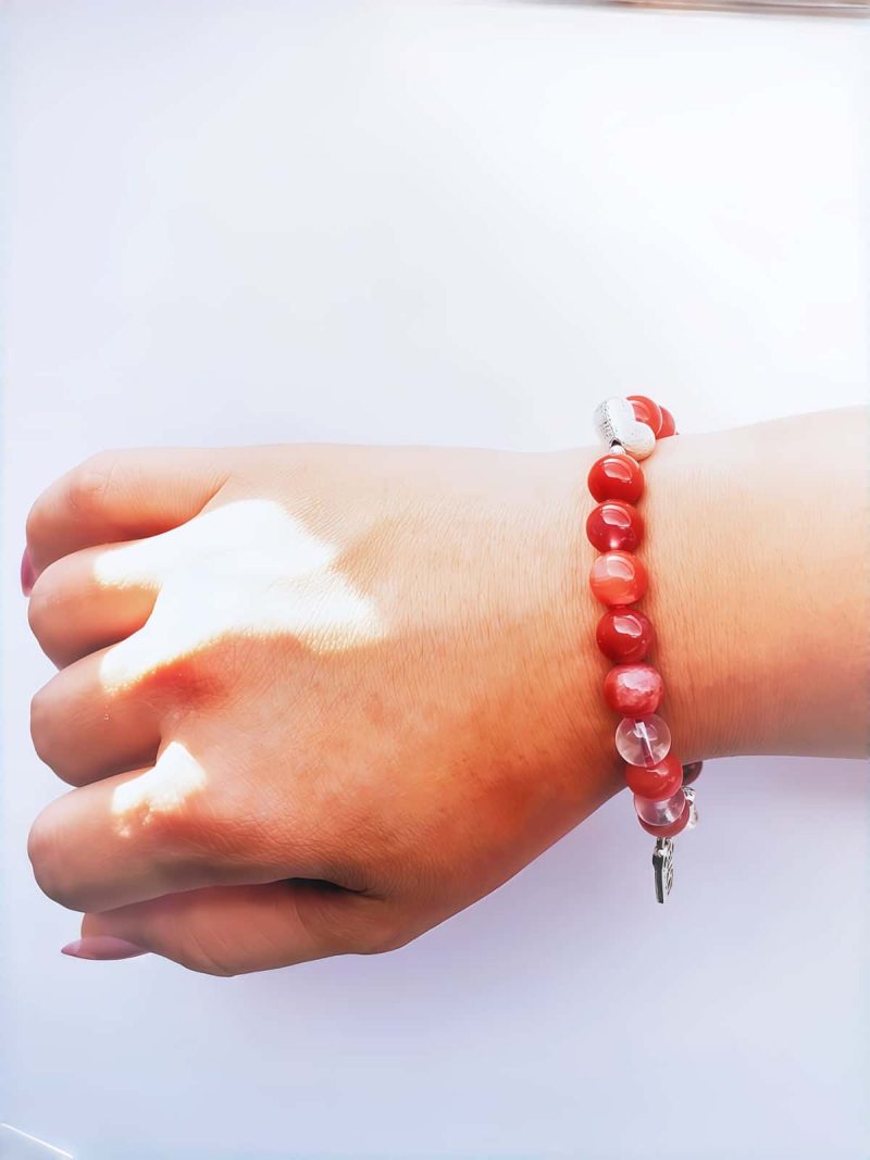 AB-ACT-03 Damenarmband aus rotem Achat Kugeln Bergkristall fein poliert versiberten Detals mit chinesischen Schriftzeichen getragen am Handgelenk bei Tageslicht