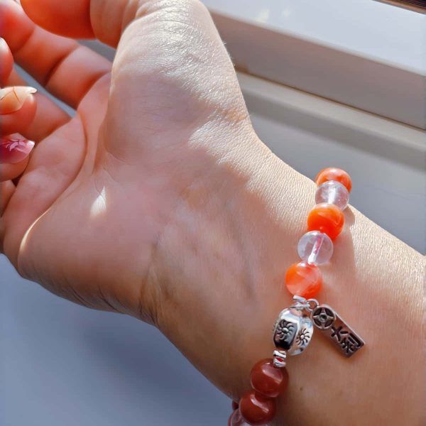 AB-ACT-04 Damenarmband aus rotem Achat Kugeln Bergkristall fein poliert versiberten Detals mit chinesischen Schriftzeichen getragen am Handgelenk bei Sonnenschein