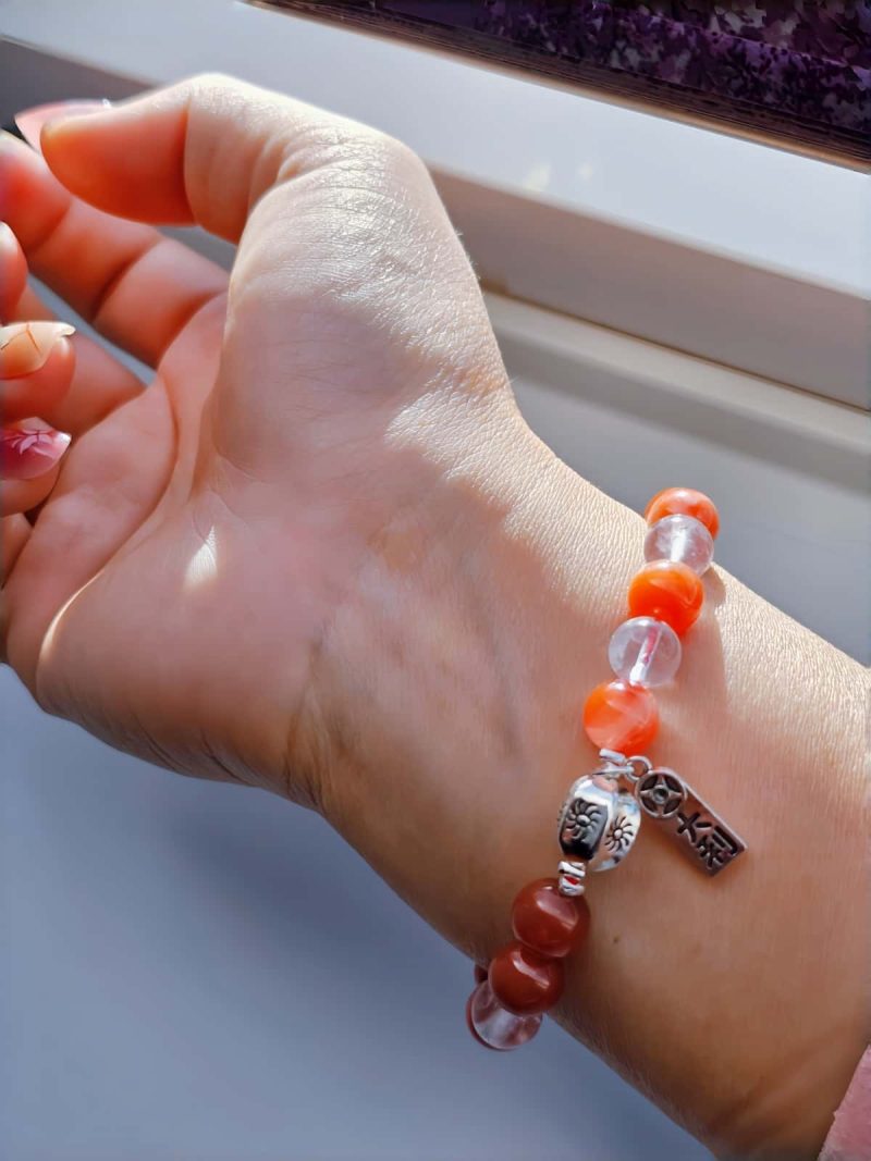 AB-ACT-04 Damenarmband aus rotem Achat Kugeln Bergkristall fein poliert versiberten Detals mit chinesischen Schriftzeichen getragen am Handgelenk bei Sonnenschein