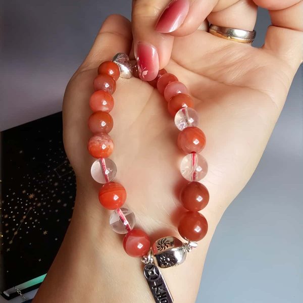 AB-ACT-08 Damenarmband aus rotem Achat Kugeln Bergkristall fein poliert versilberten Details mit chinesischen Schriftzeichen in der offenen Hand gezeigt