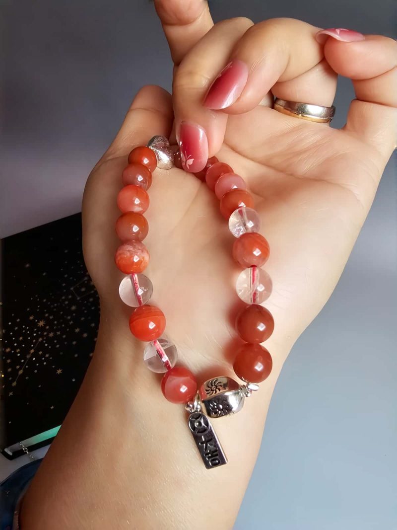 AB-ACT-08 Damenarmband aus rotem Achat Kugeln Bergkristall fein poliert versilberten Details mit chinesischen Schriftzeichen in der offenen Hand gezeigt