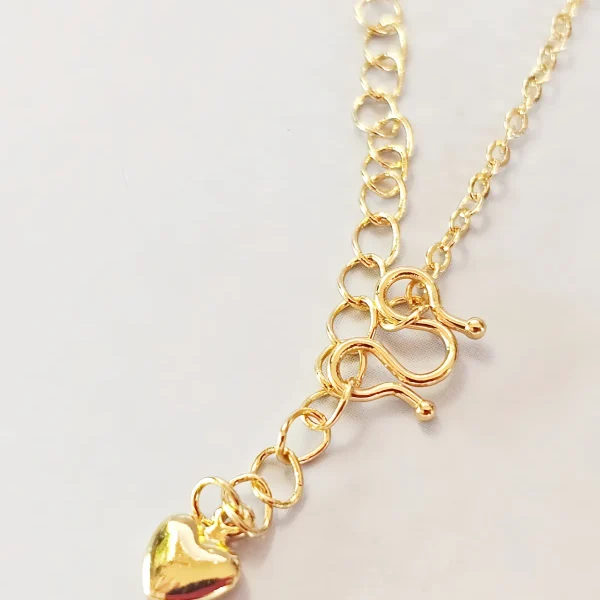 Elegante Goldene Tropfen-Fransen Halskette – Vintage Laser-Design mit schimmernden Kugeln Goldfarbene Modeschmuck-Halskette aus Kupfer, bestehend aus einer feinen Kette und einem mittigen Anhänger mit drei geriffelten Laser-Kugeln, von denen fünf filigrane Ketten mit kleinen Tropfen-Anhängern herabfallen.