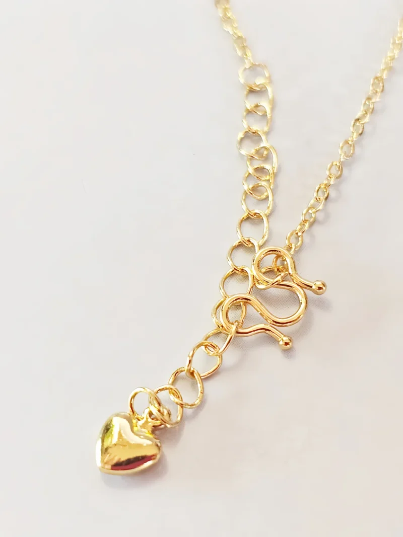 Elegante Goldene Tropfen-Fransen Halskette – Vintage Laser-Design mit schimmernden Kugeln Goldfarbene Modeschmuck-Halskette aus Kupfer, bestehend aus einer feinen Kette und einem mittigen Anhänger mit drei geriffelten Laser-Kugeln, von denen fünf filigrane Ketten mit kleinen Tropfen-Anhängern herabfallen.