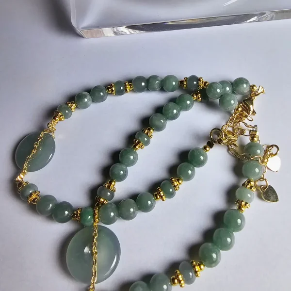 Blauwasser Jade Armband Naturstein Handgefertigtes Jade Armband aus blau-grünen Jade-Perlen mit goldenen Trennperlen und einem runden Jade-Anhänger (Ping-An-Knopf). Eleganter Schmuck mit traditioneller chinesischer Symbolik.