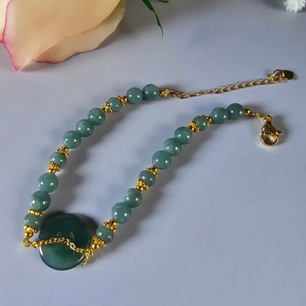 Blauwasser Jade Armband Naturstein Handgefertigtes Jade Armband aus blau-grünen Jade-Perlen mit goldenen Trennperlen und einem runden Jade-Anhänger (Ping-An-Knopf). Eleganter Schmuck mit traditioneller chinesischer Symbolik.