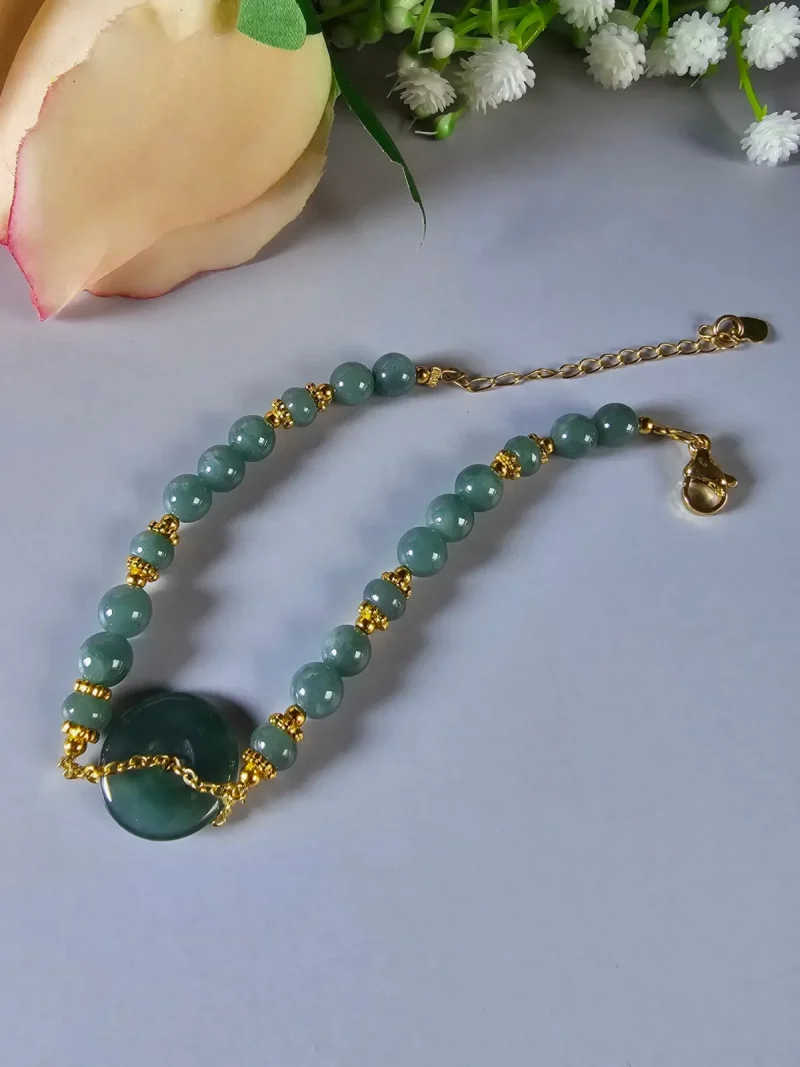 Blauwasser Jade Armband Naturstein Handgefertigtes Jade Armband aus blau-grünen Jade-Perlen mit goldenen Trennperlen und einem runden Jade-Anhänger (Ping-An-Knopf). Eleganter Schmuck mit traditioneller chinesischer Symbolik.