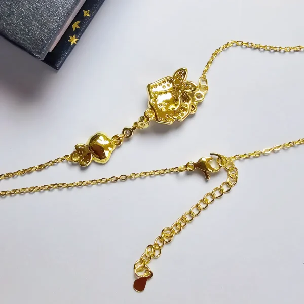 Luxuriöse Rosengold-Halskette mit Kristallbesatz – Filigranes Doppel-Blüten Design Nahaufnahme einer goldfarbenen Halskette aus Kupfer. Der Anhänger zeigt zwei stilisierte Rosenblüten: Eine Blüte ist glatt und poliert, die andere ist dicht mit kleinen, funkelnden Kristallen (Pavé-Optik) besetzt und hat einen größeren Kristall in der Mitte. Die Kette verbindet die Elemente mit kleinen, runden Kristallsteinen.