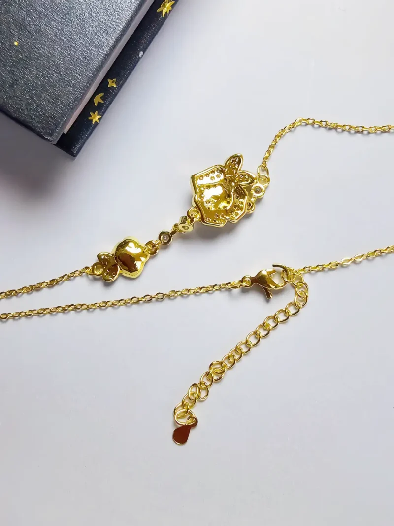 Luxuriöse Rosengold-Halskette mit Kristallbesatz – Filigranes Doppel-Blüten Design Nahaufnahme einer goldfarbenen Halskette aus Kupfer. Der Anhänger zeigt zwei stilisierte Rosenblüten: Eine Blüte ist glatt und poliert, die andere ist dicht mit kleinen, funkelnden Kristallen (Pavé-Optik) besetzt und hat einen größeren Kristall in der Mitte. Die Kette verbindet die Elemente mit kleinen, runden Kristallsteinen.