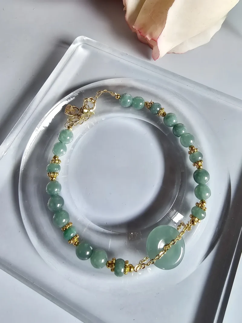 Blauwasser Jade Armband Naturstein -PER-02-03 Handgefertigtes Jade Armband aus blau-grünen Jade-Perlen mit goldenen Trennperlen und einem runden Jade-Anhänger (Ping-An-Knopf). Eleganter Schmuck mit traditioneller chinesischer Symbolik.