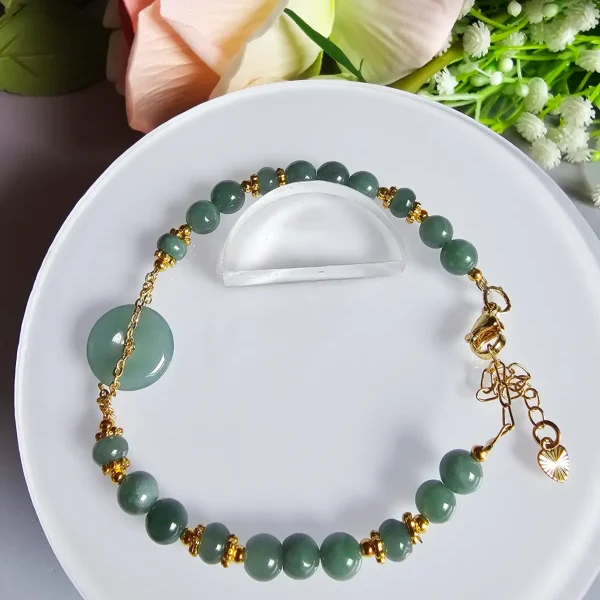 Blauwasser Jade Armband Naturstein Handgefertigtes Jade Armband aus blau-grünen Jade-Perlen mit goldenen Trennperlen und einem runden Jade-Anhänger (Ping-An-Knopf). Eleganter Schmuck mit traditioneller chinesischer Symbolik.