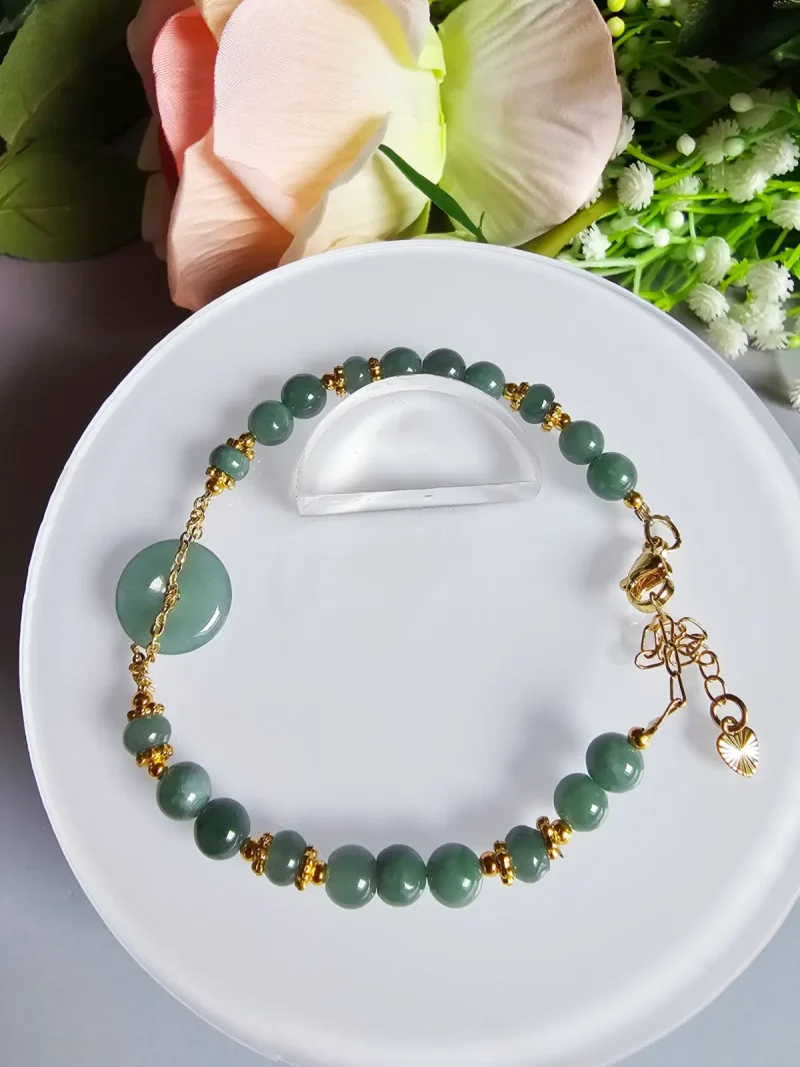 Blauwasser Jade Armband Naturstein Handgefertigtes Jade Armband aus blau-grünen Jade-Perlen mit goldenen Trennperlen und einem runden Jade-Anhänger (Ping-An-Knopf). Eleganter Schmuck mit traditioneller chinesischer Symbolik.