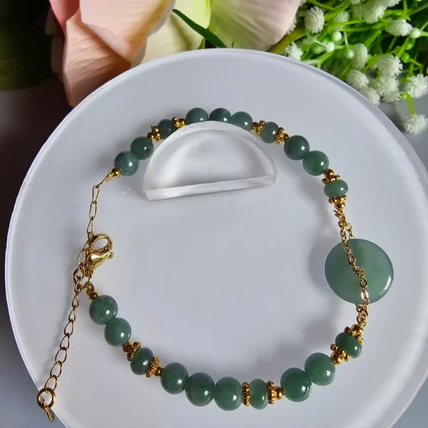Blauwasser Jade Armband Naturstein Handgefertigtes Jade Armband aus blau-grünen Jade-Perlen mit goldenen Trennperlen und einem runden Jade-Anhänger (Ping-An-Knopf). Eleganter Schmuck mit traditioneller chinesischer Symbolik.
