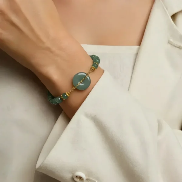 Jade Perlenarmband Blauwasser Jade Ping-an Nahaufnahme einer Frauenhand mit einem Jade Damenarmband auf dem Armgelenke präsentiert. Das Jade Armband hat eine Pingan Kou in der Mitte besetzt, mit Bedeutungen Sicherheit und Glück.