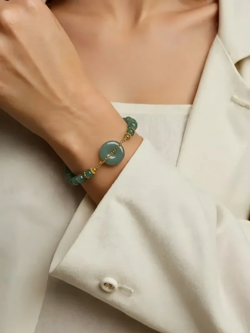 Jade Perlenarmband Blauwasser Jade Ping-an Nahaufnahme einer Frauenhand mit einem Jade Damenarmband auf dem Armgelenke präsentiert. Das Jade Armband hat eine Pingan Kou in der Mitte besetzt, mit Bedeutungen Sicherheit und Glück.