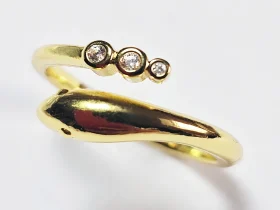 Goldener Schlangenring mit Zirkonia-Besatz Goldener Ring im Schlangen-Design mit drei runden Zirkonia-Steinen auf weißem Hintergrund.