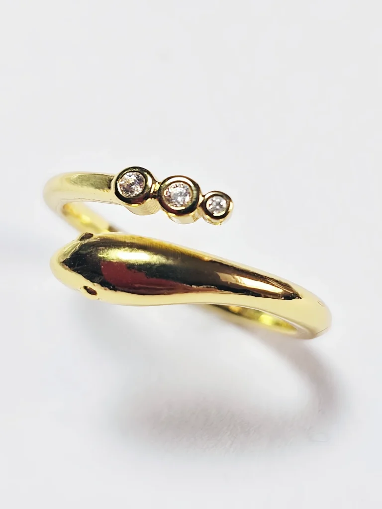 Goldener Schlangenring mit Zirkonia – Dein neues Lieblingsstück Goldener Ring im Schlangen-Design mit drei runden Zirkonia-Steinen auf weißem Hintergrund.