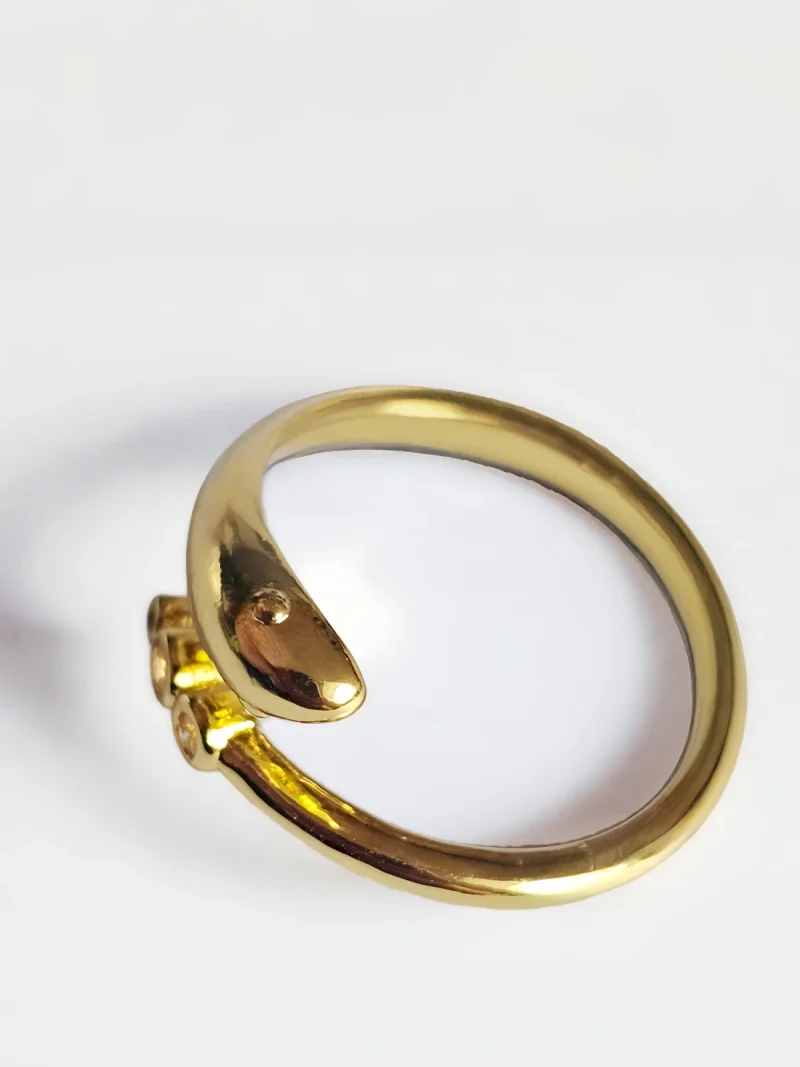 Goldener Ring im Schlangen-Design mit drei runden Zirkonia-Steinen auf weißem Hintergrund.