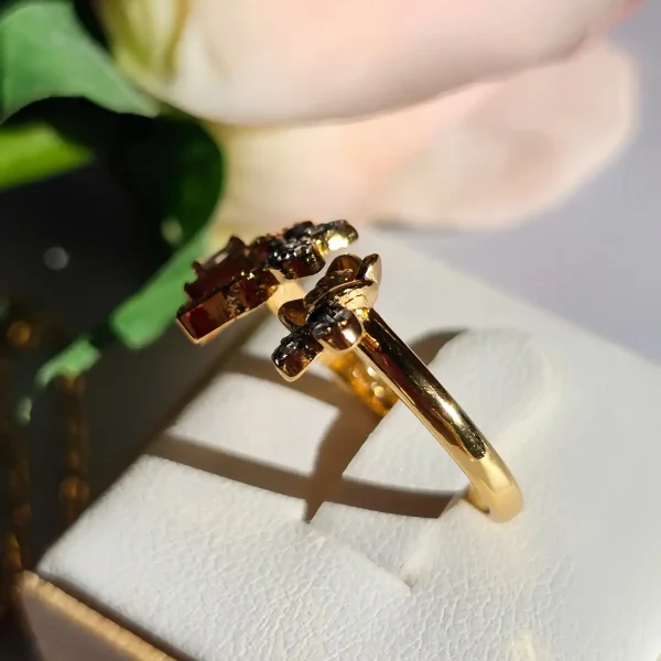 Luxuriöse Halskette und Damenring Set mit Kristallbesatz – Filigranes Doppel-Blüten Design Nahaufnahme einer goldfarbenen Damenring. Der Set zeigt zwei stilisierte Rosenblüten: Eine Blüte ist glatt und poliert, die andere ist dicht mit kleinen, funkelnden Kristallen (Pavé-Optik) besetzt und hat einen größeren Kristall in der Mitte.