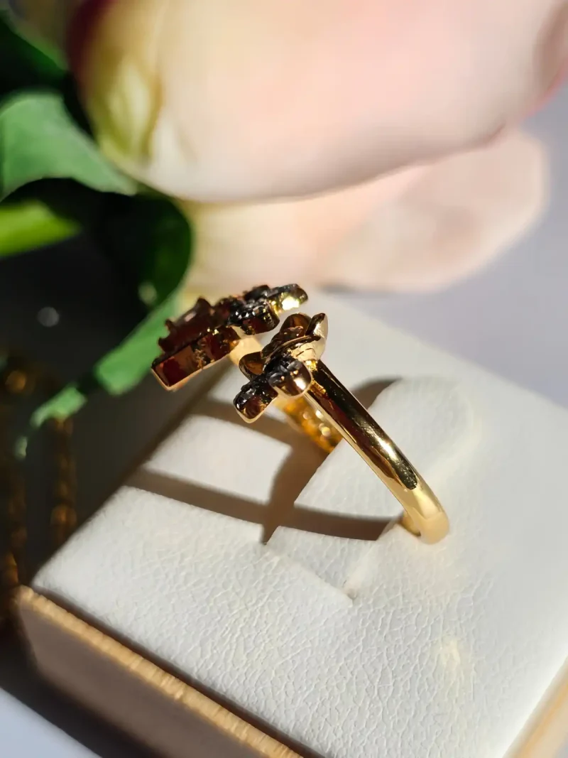 Luxuriöse Halskette und Damenring Set mit Kristallbesatz – Filigranes Doppel-Blüten Design Nahaufnahme einer goldfarbenen Damenring. Der Set zeigt zwei stilisierte Rosenblüten: Eine Blüte ist glatt und poliert, die andere ist dicht mit kleinen, funkelnden Kristallen (Pavé-Optik) besetzt und hat einen größeren Kristall in der Mitte.