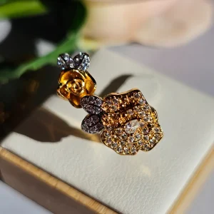 Nahaufnahme einer goldfarbenen Damenring. Der Set zeigt zwei stilisierte Rosenblüten: Eine Blüte ist glatt und poliert, die andere ist dicht mit kleinen, funkelnden Kristallen (Pavé-Optik) besetzt und hat einen größeren Kristall in der Mitte.