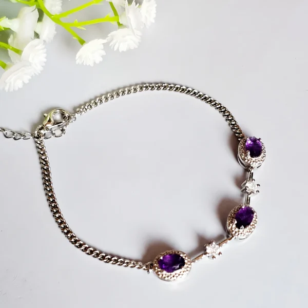Amethyst Armband aus Kupfer versilbert Amethyst Armband aus silberfarbenem Metall mit ovalen violetten Steinen und funkelnden Zirkonia-Details auf lichtblau Hintergrund mit Blumen