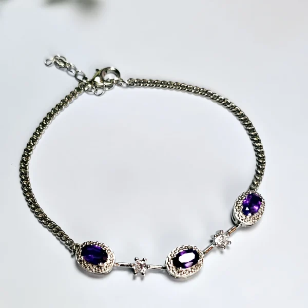 Amethyst Armband aus Kupfer versilbert Amethyst Armband aus silberfarbenem Metall mit ovalen violetten Steinen und funkelnden Zirkonia-Details auf lichtblau Hintergrund mit Blumen