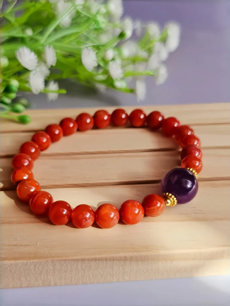ein rotes Damenarmband mit Roter Achat Naturstein und violetter Lepidolith-Zentralperle auf einem Holzplatte, vor einer Blumenhintergrund