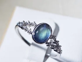 DR-SIL-03-01 Silberring mit ovalem, blau schimmerndem Mondstein und filigraner Ringschiene, verziert mit funkelnden Zirkonia-Steinen.