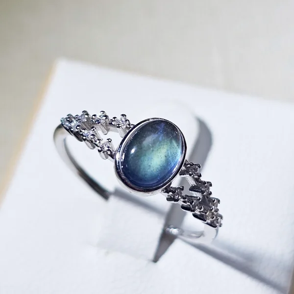DR-SIL-03-01 Silberring mit ovalem, blau schimmerndem Mondstein und filigraner Ringschiene, verziert mit funkelnden Zirkonia-Steinen.